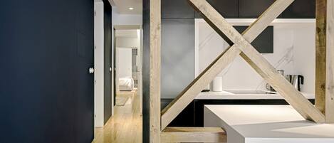 A modern kitchen with a wooden beam structure, a white countertop, and a dark wall.