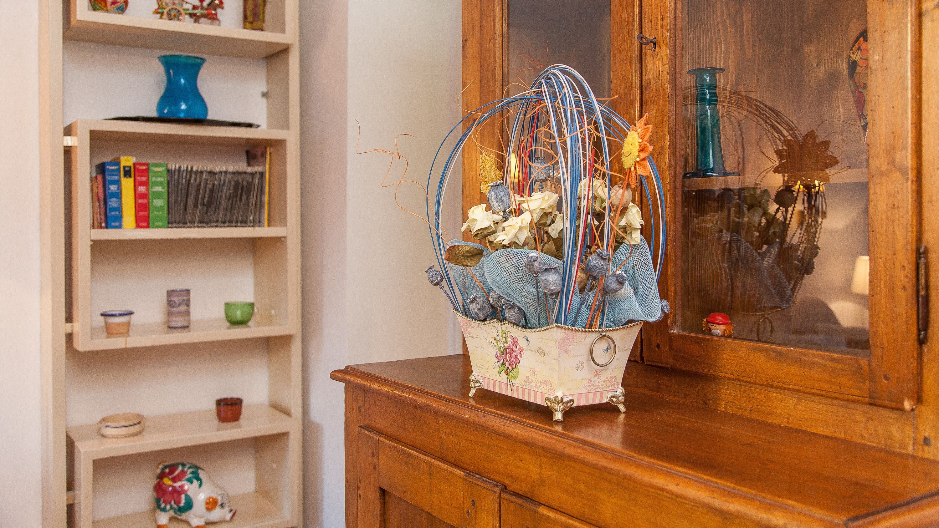 Un meuble en bois orné d’un panier décoratif contenant des fleurs séchées et un filet bleu.