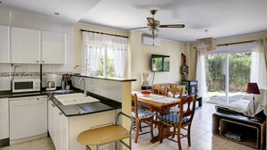 A compact kitchen with a microwave, sink, and dining area with a table and chairs. - La Rosaleda - Denia, Costa Blanca (Denia)
