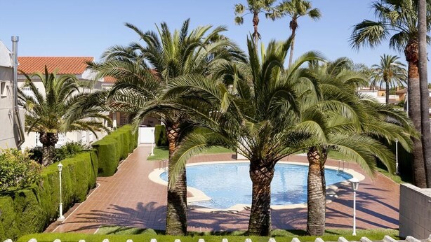 A pool area with palm trees and a tiled walkway. - La Rosaleda - Denia, Costa Blanca (Denia)