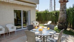 An outdoor patio with a round table, wicker chairs, and a glass-top table. - La Rosaleda - Denia, Costa Blanca (Denia)