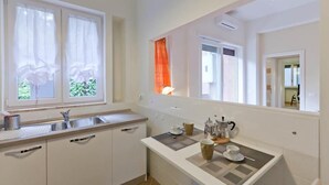Eine Küche mit Spüle, Schränken, einer Arbeitsplatte und einem Fenster mit Vorhängen.