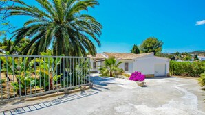 A residential property with a paved driveway, a white garage, and a palm tree. - Mimosa - pretty holiday property with private pool in Moraira (Benissa)