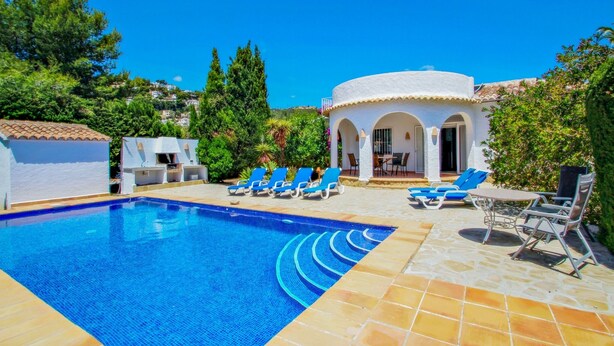 A swimming pool with blue tiles, surrounded by lounge chairs and a covered seating area with a white exterior and arches. - Mimosa - pretty holiday property with private pool in Moraira (Benissa)