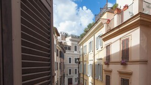 A narrow street with buildings featuring traditional architecture, including balconies with potted plants and shutters. - Navona Loft in Via dell'Orso (Rome)