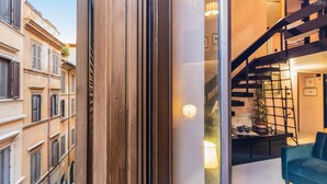 A modern interior with a staircase, a sofa, and a view of neighboring buildings. - Navona Loft in Via dell'Orso (Rome)