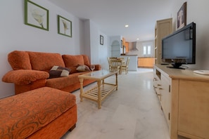 A living room with a sofa, ottoman, coffee table, and a television.
