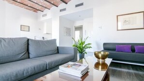 A modern living room with a grey sofa, a coffee table with a magazine, a potted plant, and a decorative bowl. - One bedroom apartment (Barcelona)