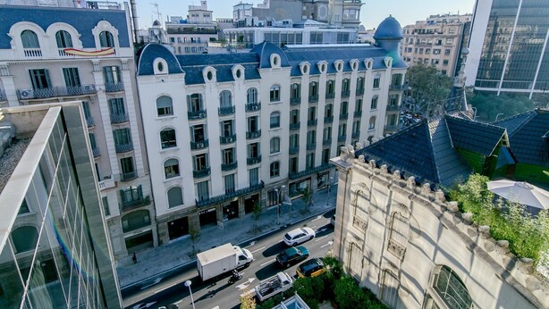 A multi-story building with a classical architectural style, featuring arched windows and a central dome. - One bedroom apartment (Barcelona)