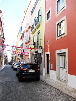 A narrow cobblestone street lined with colorful buildings, a black car parked on the side, and a sign for a restaurant named "Olea". - Contemporary by Apartments Alfama (Lisbon)
