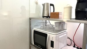 Une petite cuisine équipée d’un four à micro-ondes, d’une bouilloire et d’une machine à café, le tout placé sur une étagère.