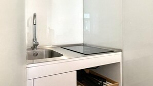 Une cuisine moderne dotée d’un évier en acier inoxydable, d’un plan de travail noir et d’un tiroir en dessous.