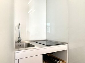 A modern kitchen with a stainless steel sink, a black countertop, and a drawer below.