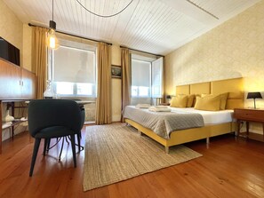 A bedroom with a bed, a desk, a chair, and a window with curtains.