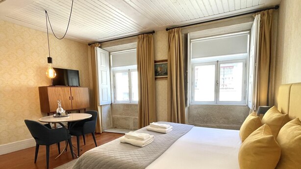 Une chambre d’hôtel avec un lit, un bureau, une chaise, une fenêtre et une vue sur l’extérieur.