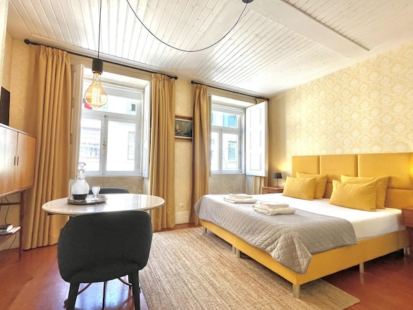 A hotel room with a bed, a desk, a chair, and a window.