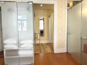 A hallway with a wooden floor, a glass door with frosted panels, and a patterned wall.