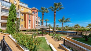 Un patio de hotel con palmeras, un pabellón y una piscina.