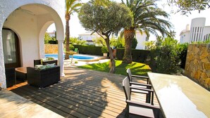 Un patio al aire libre con piscina, asientos y un muro de piedra.
