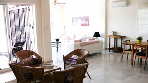 Un vaste espace de vie agrémenté de meubles en osier, d’un canapé blanc et d’une table à manger avec des chaises.