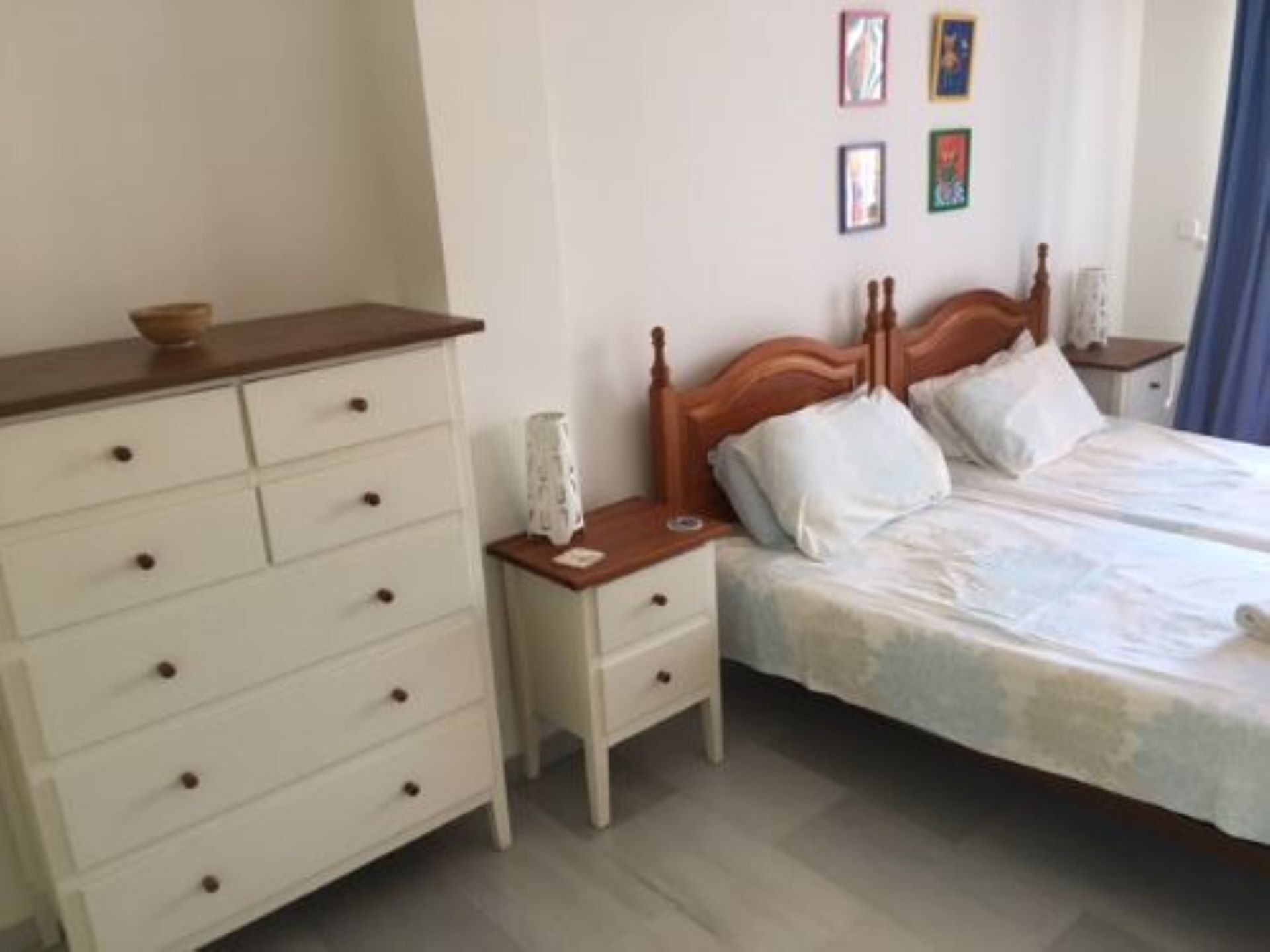 A bedroom with a wooden bed, white drawers, and a nightstand.