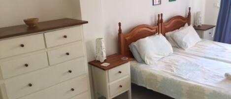 A bedroom with a wooden bed, white drawers, and a nightstand.