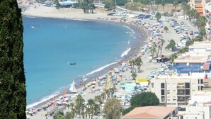 Un paysage urbain côtier avec une plage, des voitures garées et des bâtiments le long de la côte.