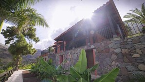 A stone-walled building with a balcony, surrounded by tropical vegetation. - Finca Horno de la Teja (Hornillo, El (Mogan))