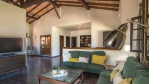A spacious living room with a large flat-screen TV, a green sofa set, a coffee table, and a wooden ceiling. - Finca Horno de la Teja (Hornillo, El (Mogan))