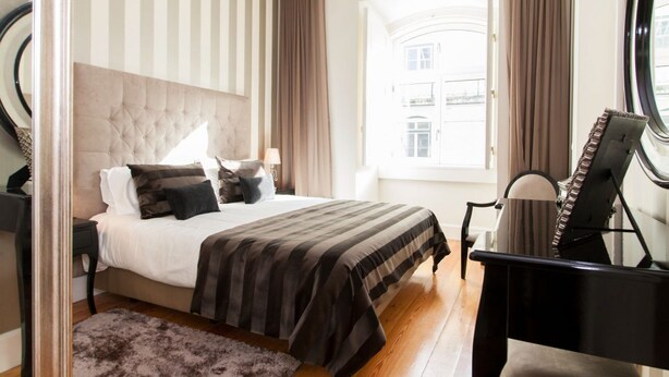 Un dormitorio con una cama, un piano, una ventana con cortinas y una araña.