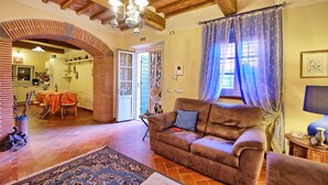 Un salón acogedor con un sofá marrón, un tapete estampado y un comedor con mesa y sillas.
