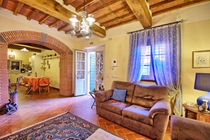 A cozy living room with a brown sofa, a patterned rug, and a dining area with a table and chairs.