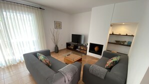 En moderne stue med to grå sofaer, et sofabord, et fjernsyn og en pejs.