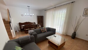 En stue med sofa, sofabord og spiseområde med bord og stole.