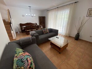 Een woonkamer met een bank, een salontafel en een eethoek met een tafel en stoelen.