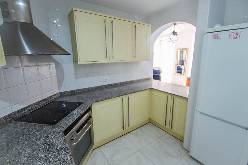 Una cocina con estufa, horno y refrigerador blanco.