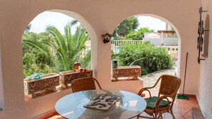 Taula de vidre amb cadires en una habitació il·luminada pel sol i amb finestres apuntades que donen a un jardí.