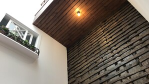 A modern interior with a wooden ceiling, a white wall, and a textured brick wall. - The Brewmaster's House 5 | Rooftop Bedroom (Porto)