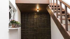 A staircase with wooden railings leading to a landing with a brick wall and a light fixture. - The Brewmaster's House 5 | Rooftop Bedroom (Porto)