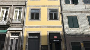 A multi-story building with a yellow facade, multiple windows, and a storefront labeled "aFabrica". - The Brewmaster's House 5 | Rooftop Bedroom (Porto)