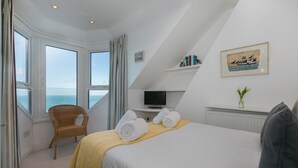 Habitación de hotel con cama, una silla, un televisor y un cuadro.