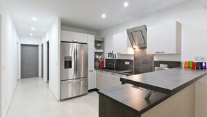 A modern kitchen with stainless steel appliances, a central island, and a built-in oven. - Le Bougainvillier, magnificent villa with breathtaking views (Oyster Pond)