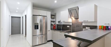 A modern kitchen with stainless steel appliances, a central island, and a built-in oven.