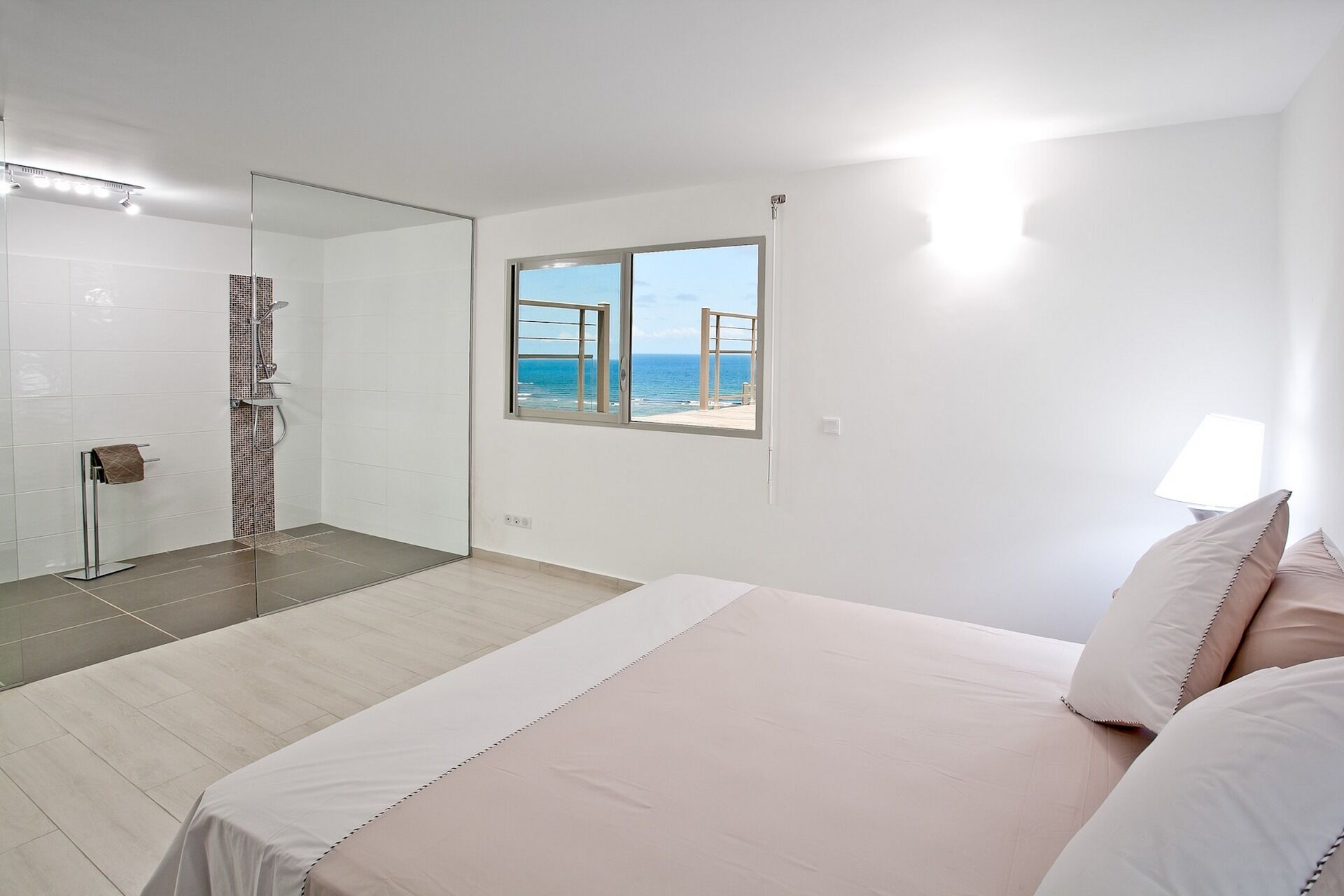 Un dormitorio con una cama grande, una ventana con vista al mar y una zona de ducha.