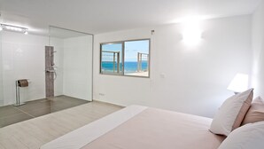 A bedroom with a large bed, a window with a view of the sea, and a shower area. - Le Bougainvillier, magnificent villa with breathtaking views (Oyster Pond)