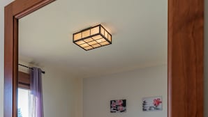 Une chambre avec un grand miroir, un lit avec deux oreillers, une table de chevet avec une lampe et des œuvres d’art accrochées au mur.