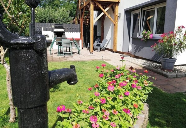 Um espaço ao ar livre residencial com jardim, churrasqueira e pérgola de madeira.