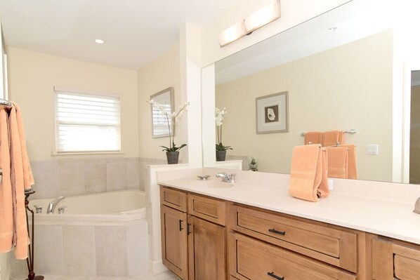 Un baño moderno con un espejo grande, una bañera y armarios de madera.