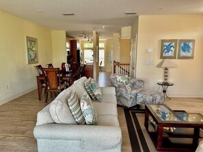A spacious living room with a grey sofa, patterned armchairs, a glass coffee table, and a dining area in the background. - Bradenton Beach Club 251 - Anna Maria Island - Condo 3 Bedroom/ 2 1/2 Bath, maximum occupancy of 6 people. (Bradenton Beach)