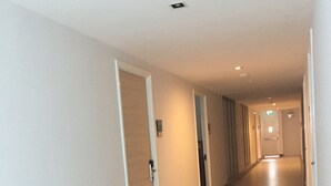 Um corredor comprido e estreito, com portas de ambos os lados, que dá acesso a quartos individuais.